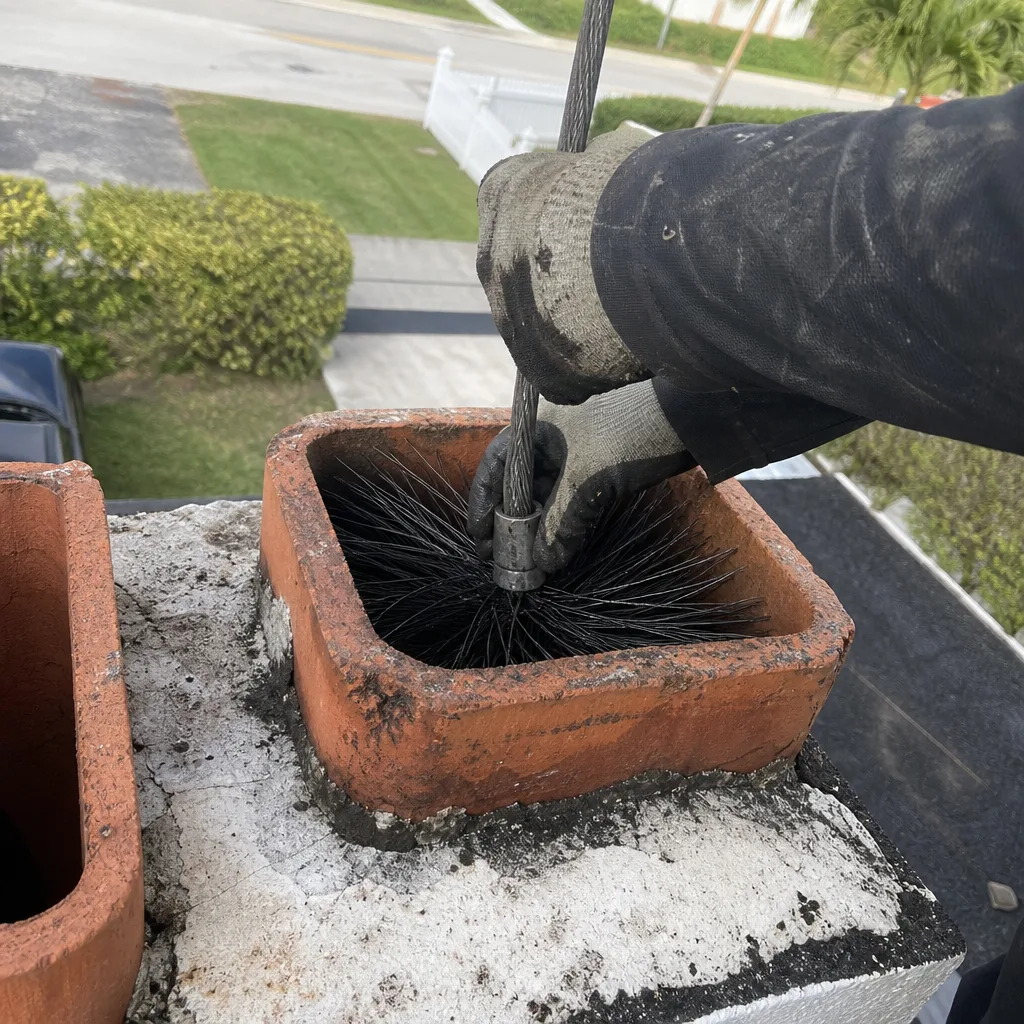 Professional chimney sweep using a chimney brush to clean a flue
